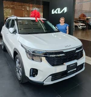 Un KIA blanco con moño rojo y una asesora