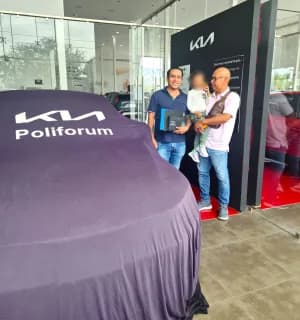 Una familia junto a un KIA cubierto con la lona de entrega